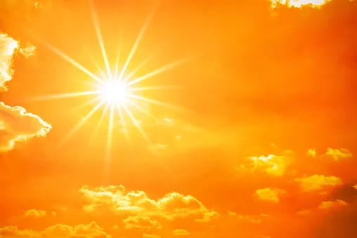 Hot summer or heat wave background, orange sky with clouds and glowing sun